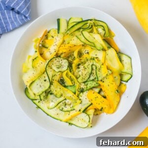 Vibrantly colorful sautéed summer squash ribbons carefully arranged in a pristine white bowl, showcasing their fresh appeal.