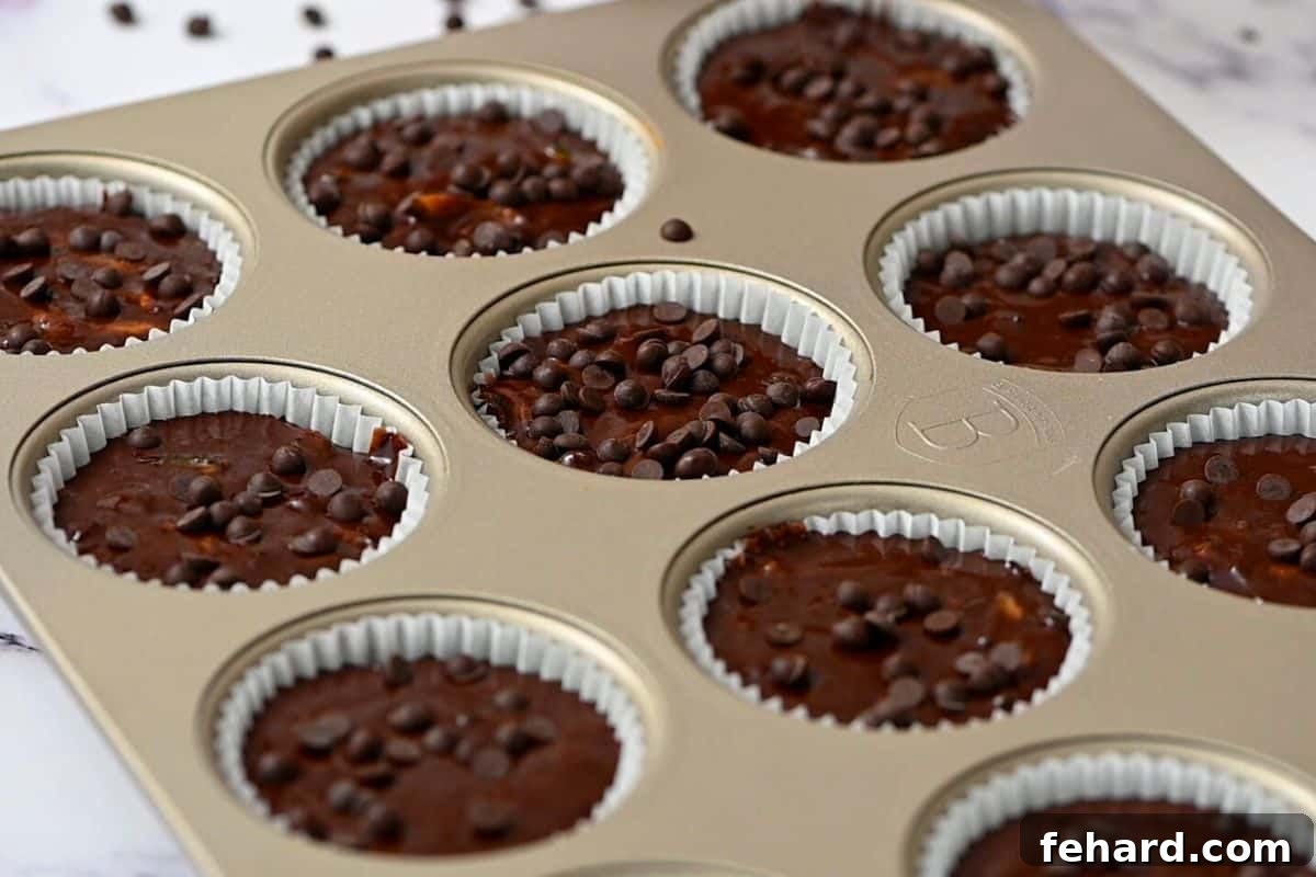 Chocolate Zucchini Muffin Batter in muffin tin topped with chocolate chips.