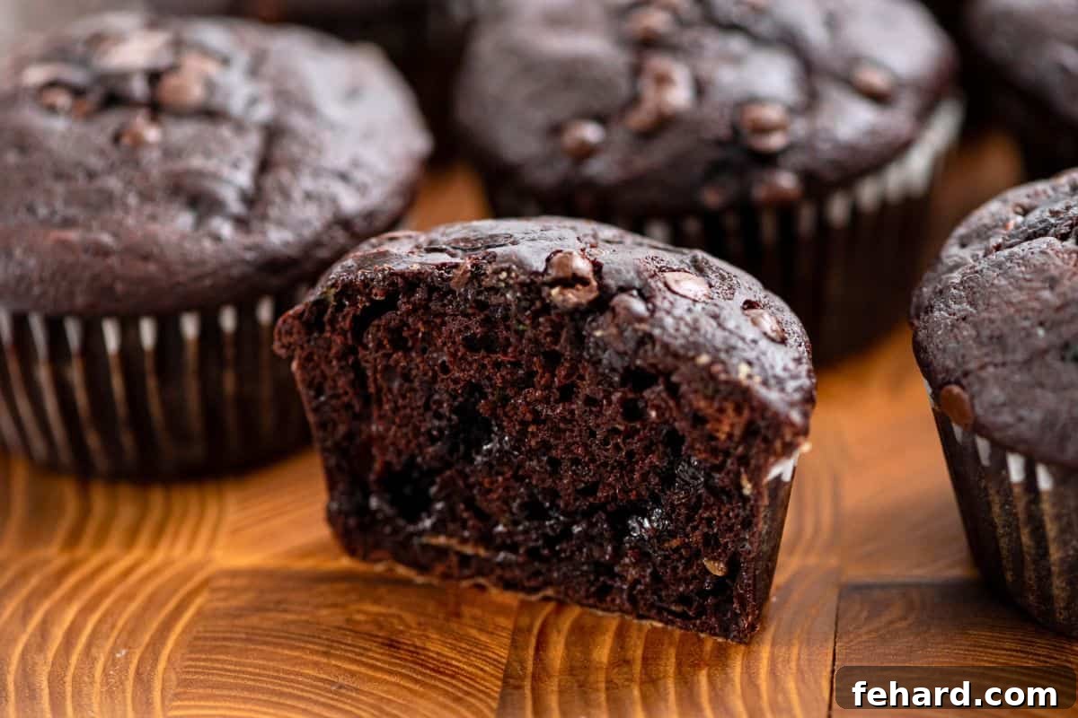 Chocolate Zucchini Muffin cut in half showing rich center with chocolate chips on cutting board.