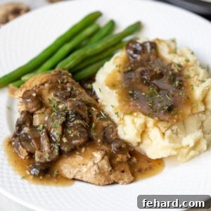Chicken Marsala on white plate with mashed potatoes and green beans