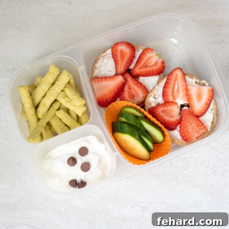 Nut-Free Sandwiches: Cream Cheese & Strawberry Bagel Strawberry Bagel with veggies and yogurt in a bento lunch container, a perfect nut-free sandwich alternative.