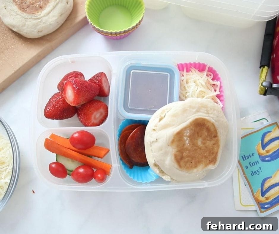 Peanut-Free Lunch Ideas: DIY Pizza Kit Lunch Container with English Muffin, shredded cheese, and pizza sauce with fruit and veggies, illustrating a homemade nut-free pizza lunchable.
