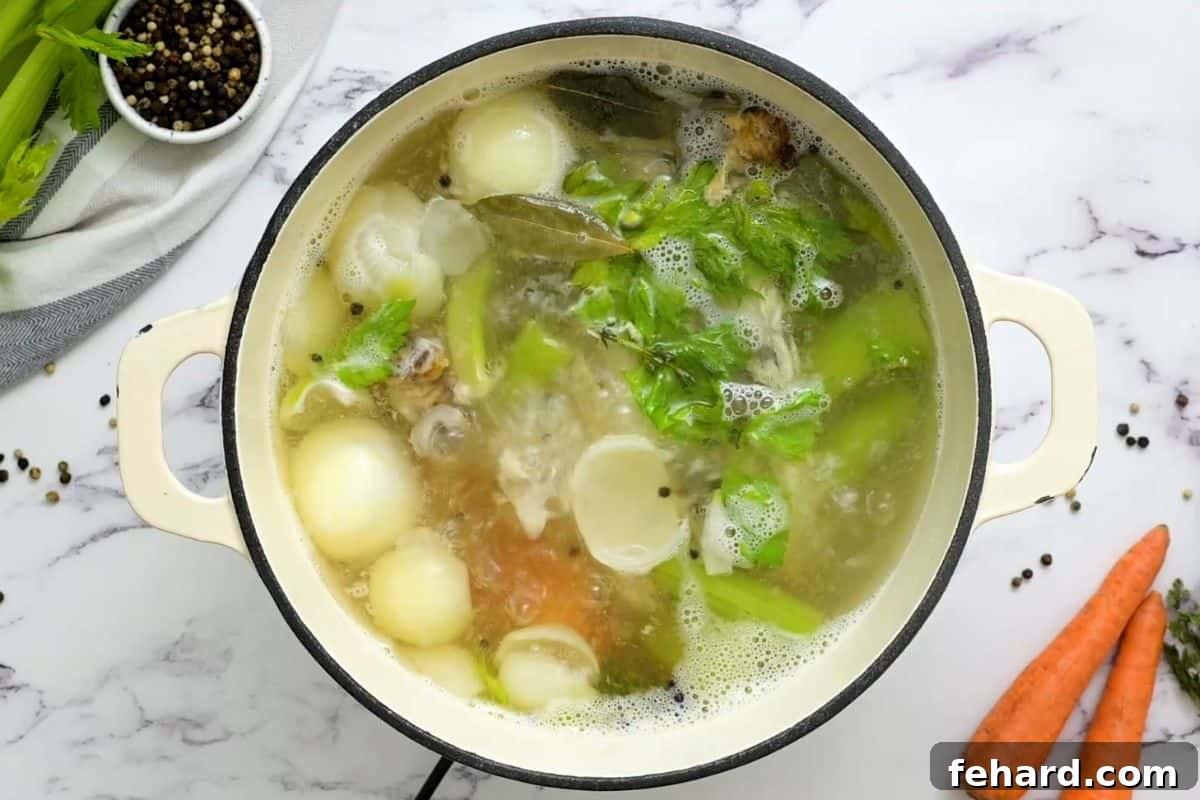 Chicken stock gently simmering in a large Dutch oven pot on the stove.