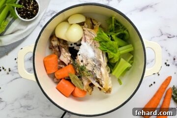 Chicken bones, carrots, celery, salt, bay leaves, and onion placed in a stockpot, covered with water, before cooking.