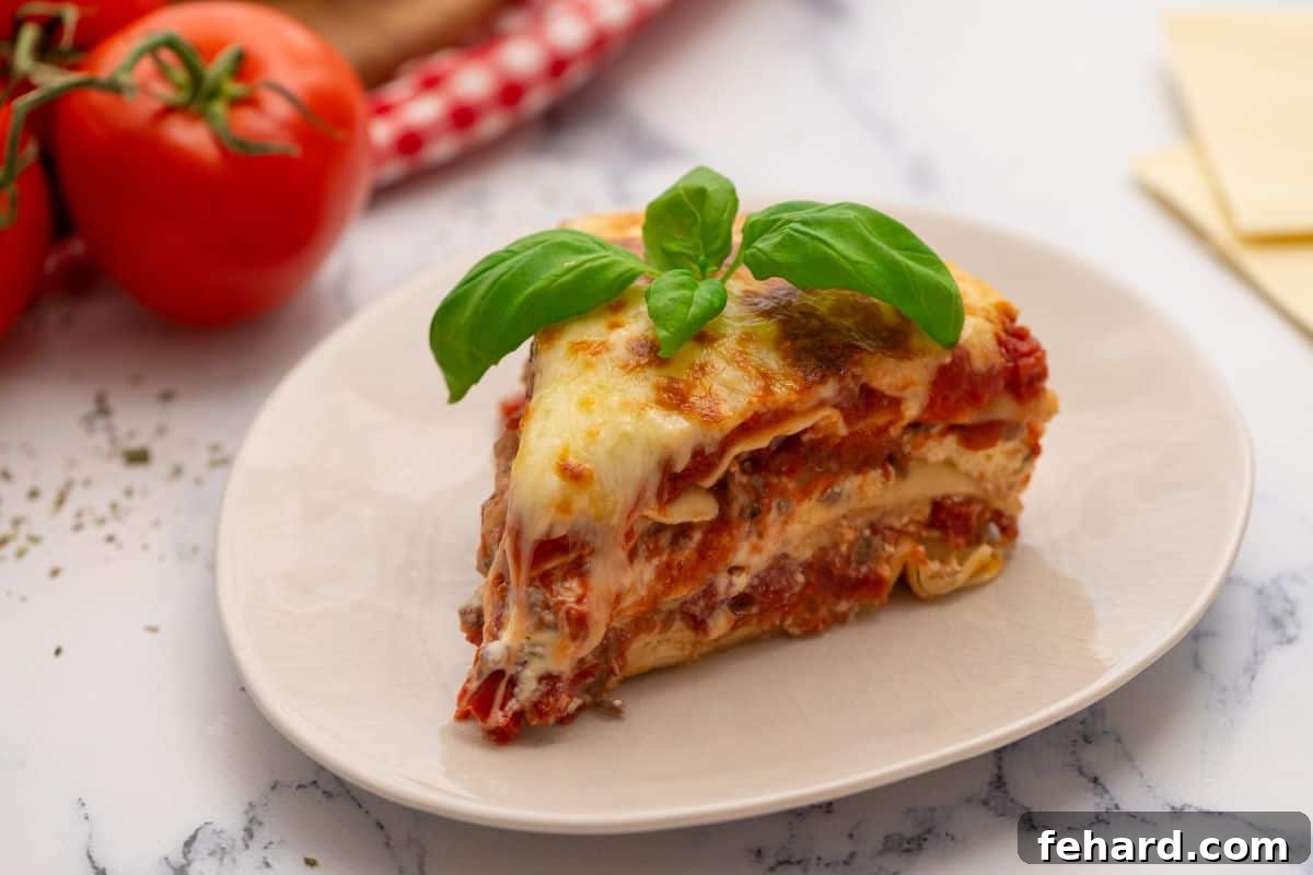 A perfectly sliced piece of Instant Pot Lasagna, topped with fresh basil, on a white plate.