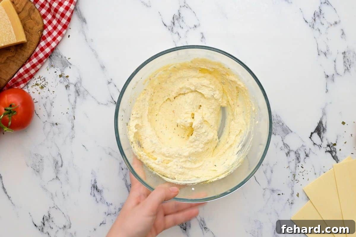 Ricotta cheese mixture in a bowl, containing egg, seasonings, and parmesan cheese, ready for assembly.