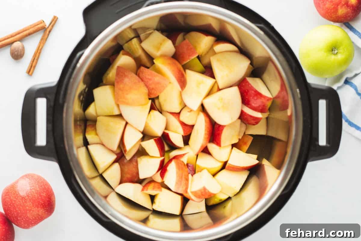 Sweet, soft apples cut into large chunks inside inner pot of Instant Pot with apple juice inside.