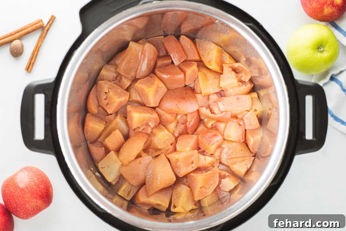 Cooked apples inside inner pot after pressure cooking, next to fresh apples.