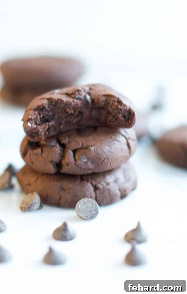 A stack of three gluten free chocolate chunk cookies, one with a bite taken out, revealing its soft interior.