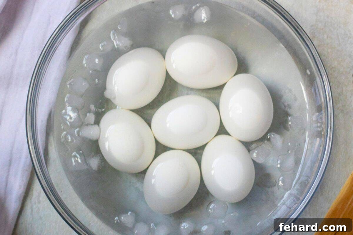 Seven Instant Pot hard-boiled eggs cooling down in a bowl of ice water on a kitchen counter.