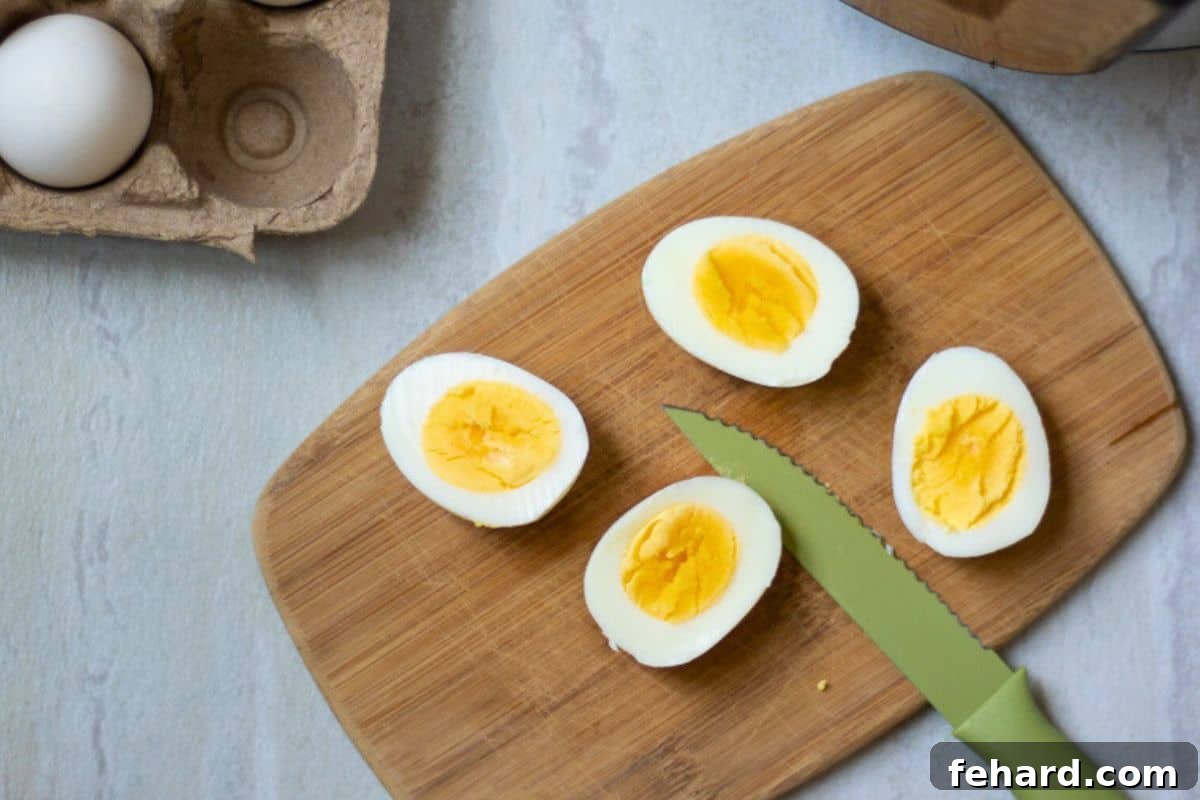 Two perfect Instant Pot Hard Boiled Eggs, sliced open to reveal ideal set whites and creamy golden yolks, next to the Instant Pot.