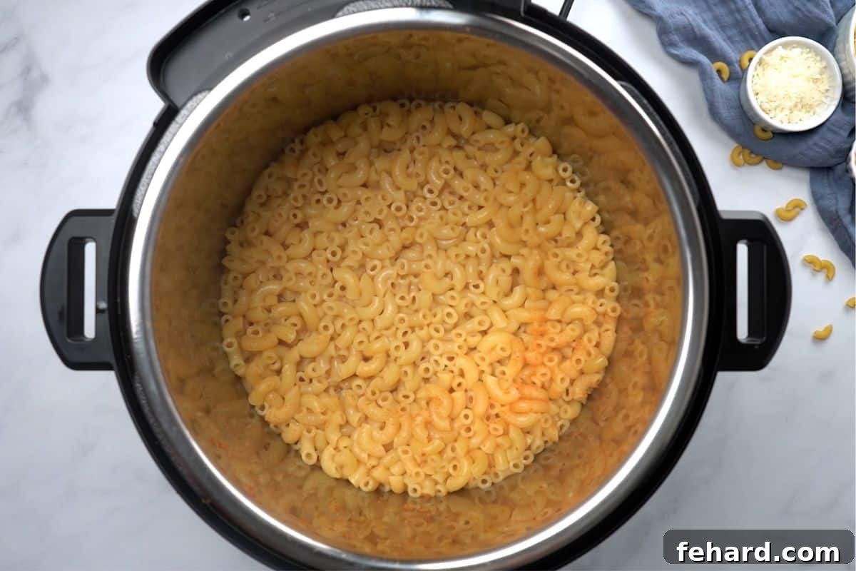 The Instant Pot open, revealing perfectly cooked, plump elbow noodles, signifying the ideal consistency achieved after precise pressure cooking.
