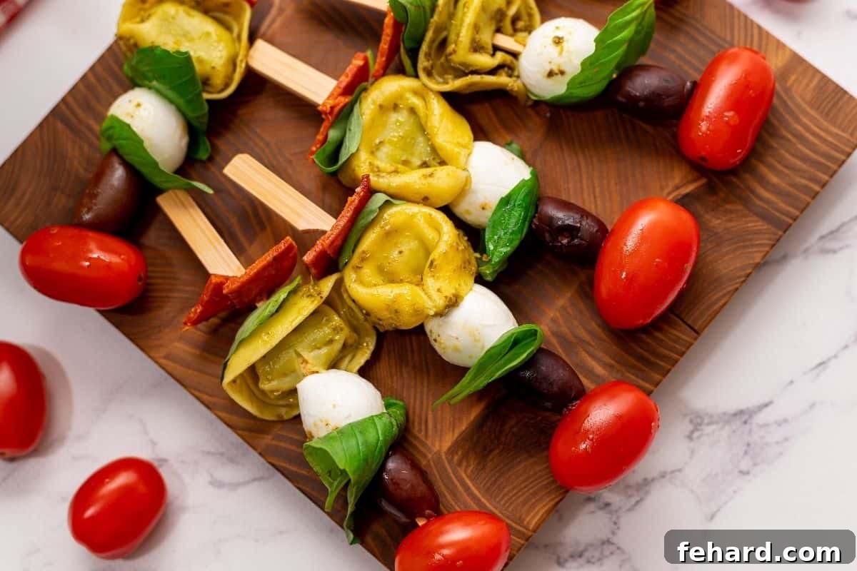 Finished Antipasto Skewers neatly arranged on a rustic wooden platter, showcasing cherry tomatoes, mozzarella, tortellini, basil, and pepperoni.