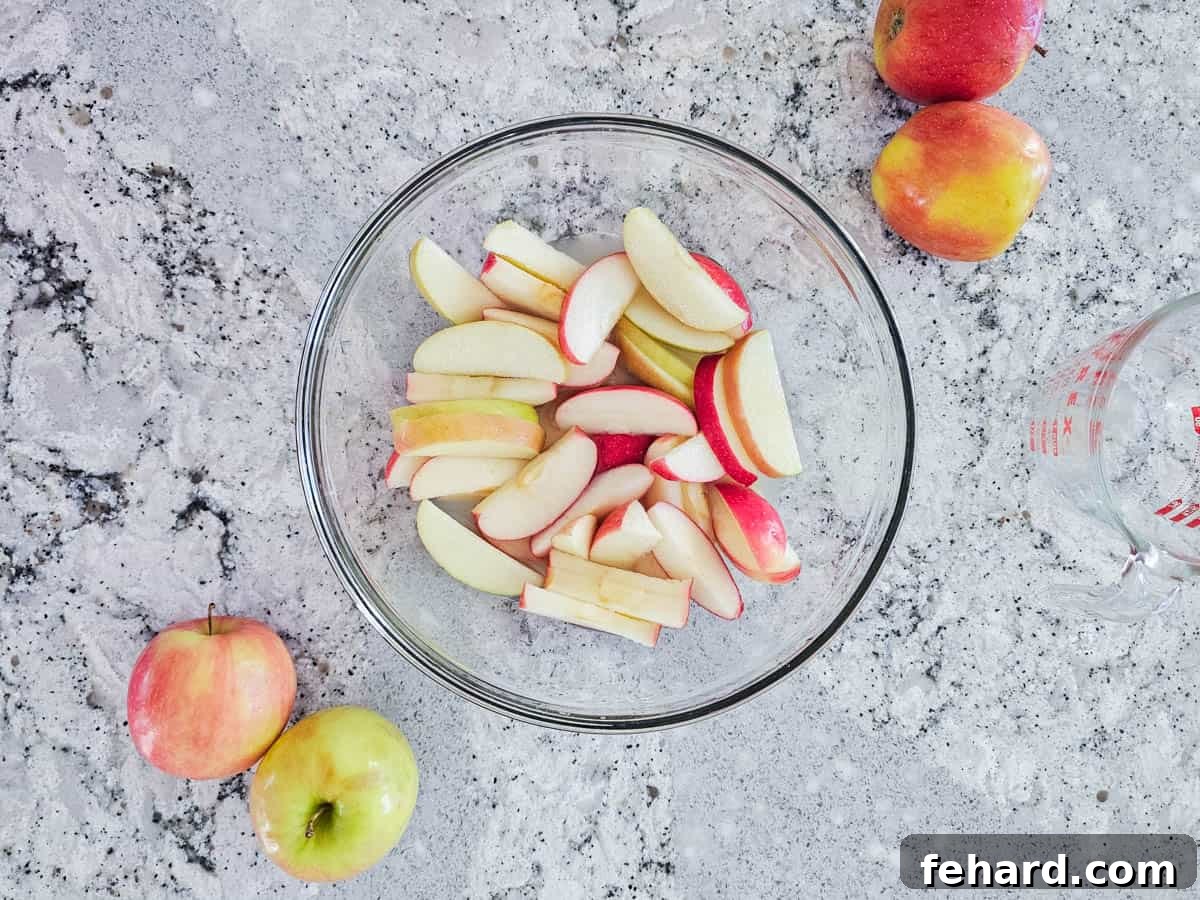 Apple Dip Recipe with Cream Cheese and Fresh Apples A variety of crisp, sliced apples submerged in pineapple juice in a mixing bowl, a method to prevent browning.