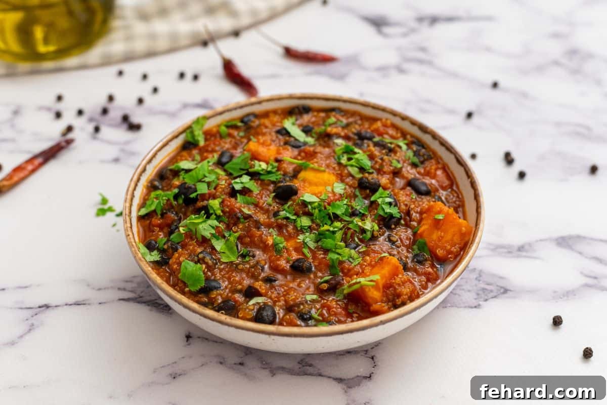 Serving Sweet Potato Quinoa Chili with Fresh Toppings A beautifully presented bowl of sweet potato black bean chili, elegantly topped with vibrant minced cilantro, ready to be enjoyed.