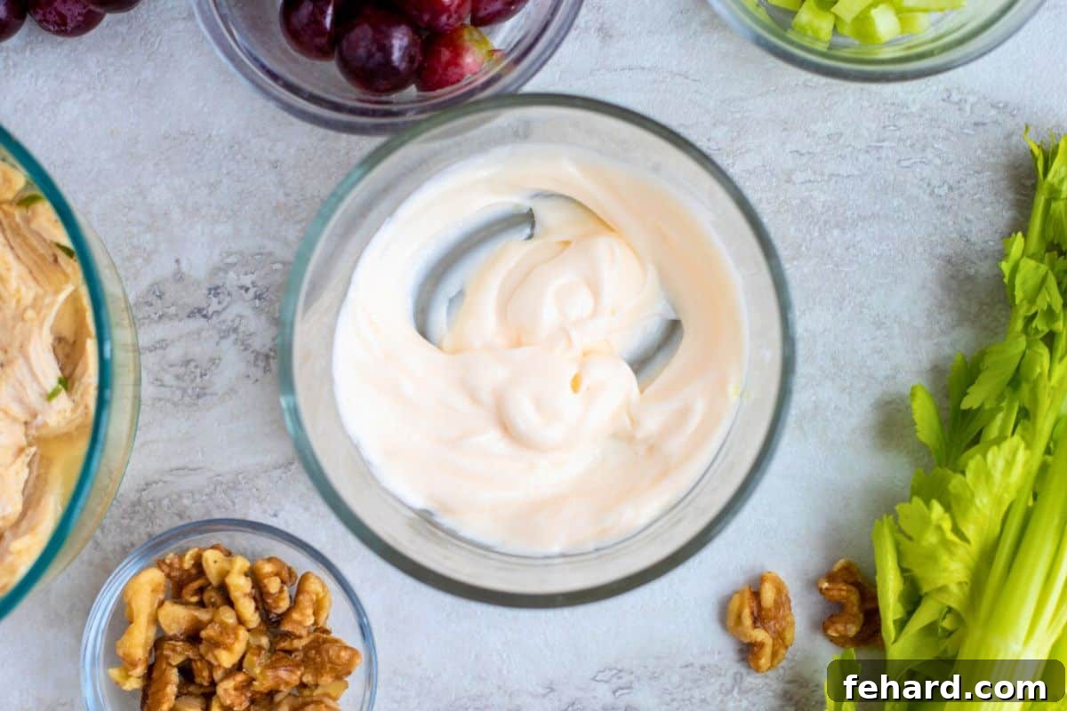 Dressing for chickens salad with mayo and yogurt mixed together in mixing bowl.
