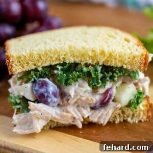 Waldorf Chicken Salad on thick white bread topped with curly kale on cutting board.
