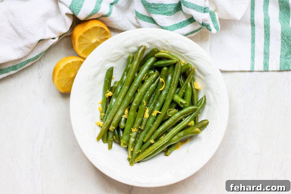 Perfect Instant Pot Green Beans 3 Perfectly steamed Instant Pot green beans in a white bowl, garnished with bright lemon zest and a squeeze of fresh lemon juice.