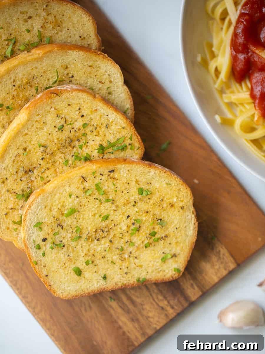 Toasted garlic bread on cutting board topped with fresh parsley, ready to serve.