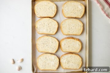 Garlic butter slathered on slices of bread on baking sheet.