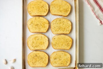 Toasted Garlic Toast on sheet pan next to fresh garlic cloves.