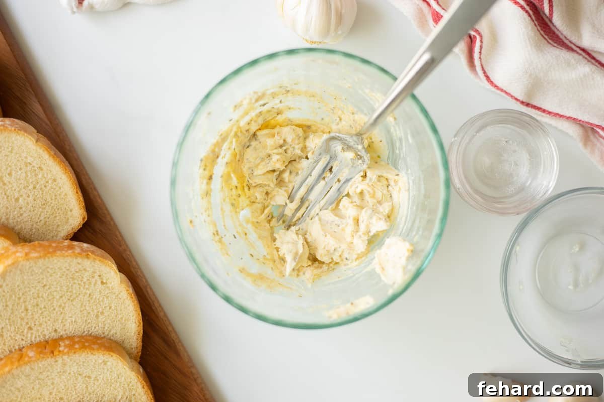 Softened butter mixed with garlic powder, oregano, and salt in a bowl, with thick bread slices nearby.