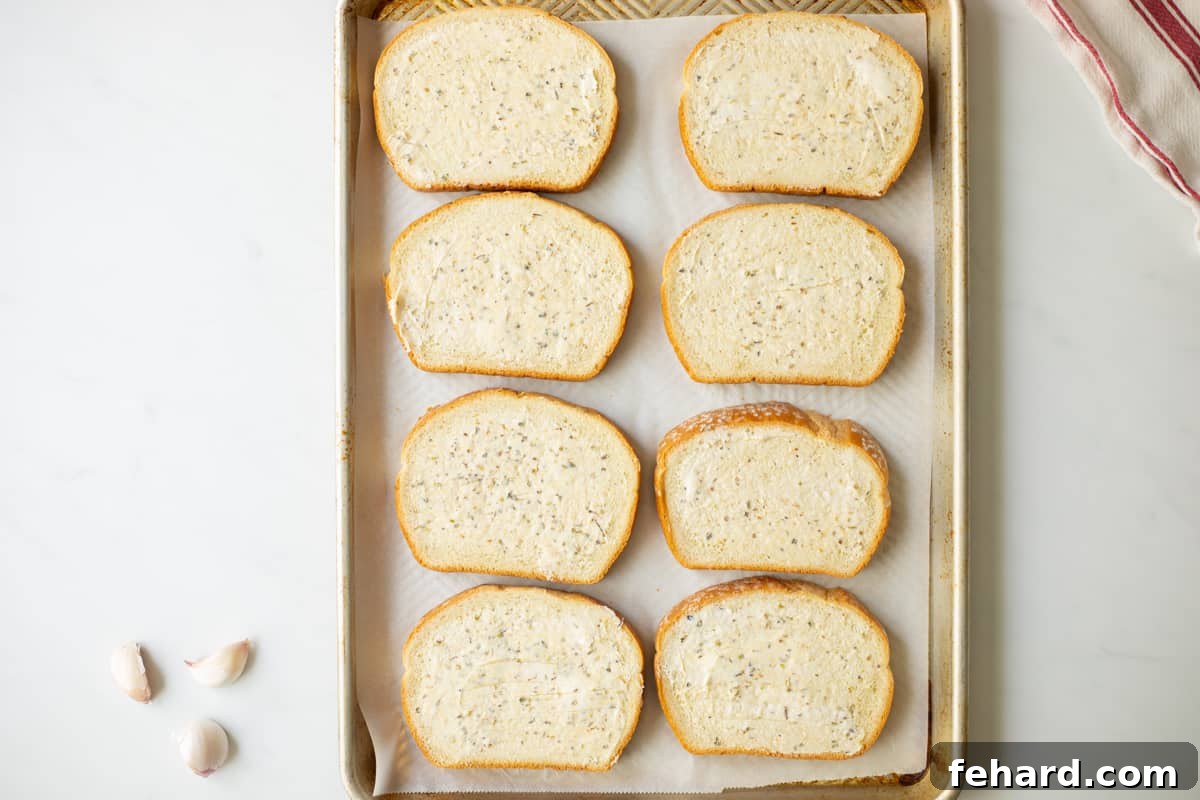 Garlic butter generously spread on bread slices on a parchment-lined baking sheet.
