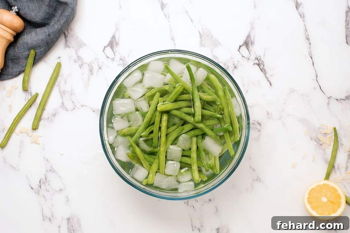 Green beans submerged in an ice bath, showcasing their vibrant green color after blanching.