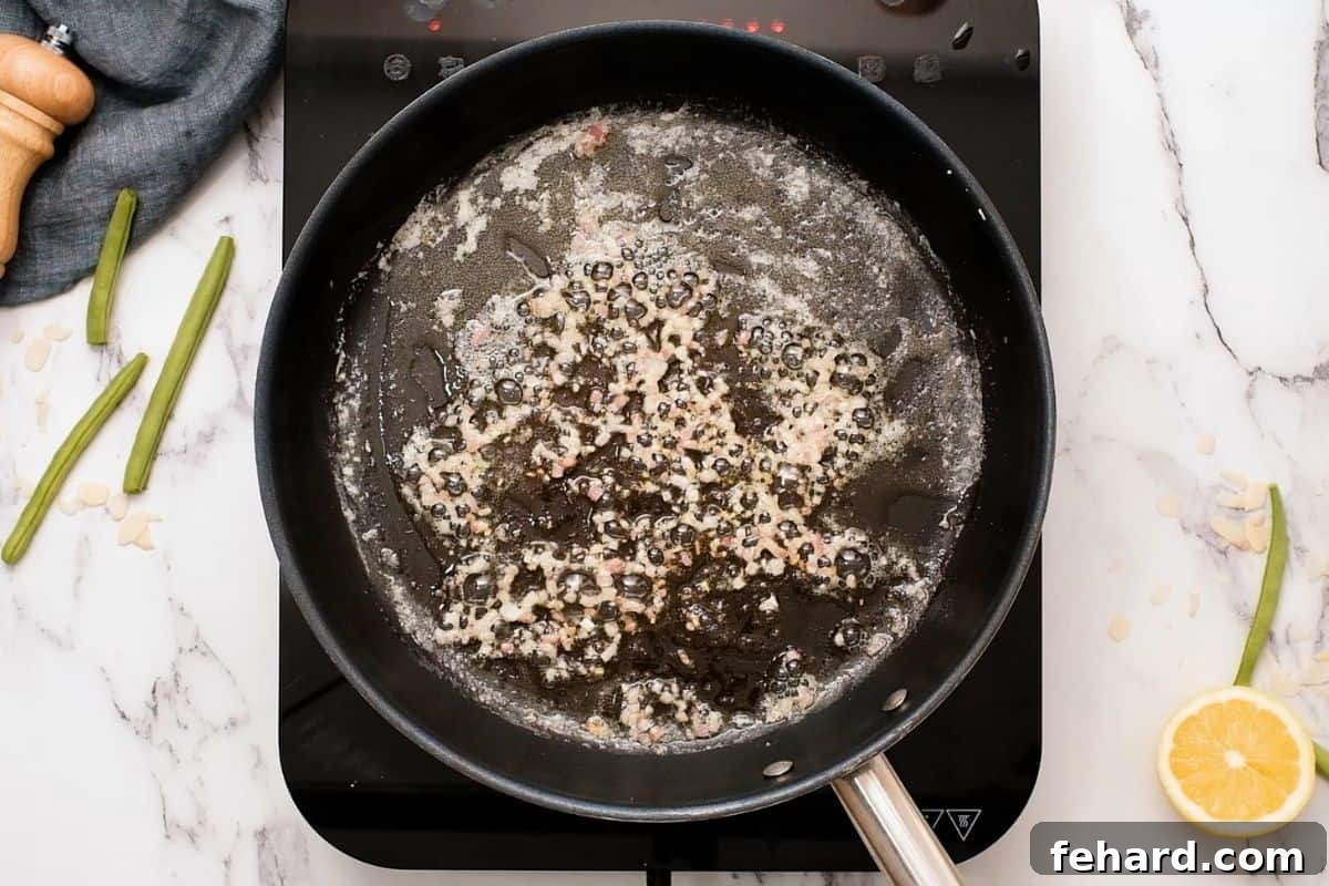 Finely minced shallots sautéing in melted butter in a skillet, creating an aromatic base.
