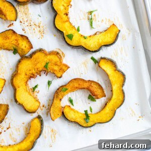 Slices of Maple Roasted acorn squash on parchment paper topped with minced parsley.