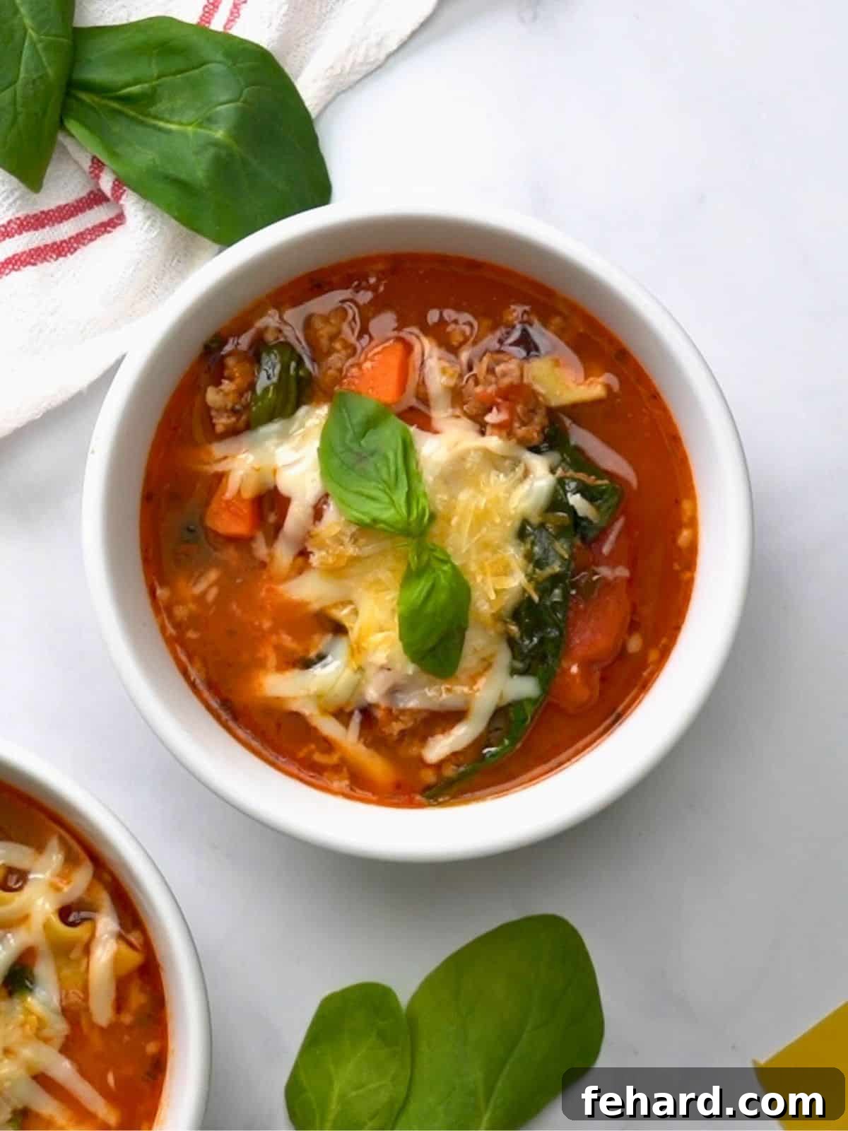 A steaming bowl of Instant Pot Lasagna Soup, garnished with melted mozzarella and grated parmesan cheese, fresh parsley, and a piece of garlic toast on the side. The soup contains hearty Italian sausage, tender spinach, and broken lasagna noodles in a rich tomato broth.