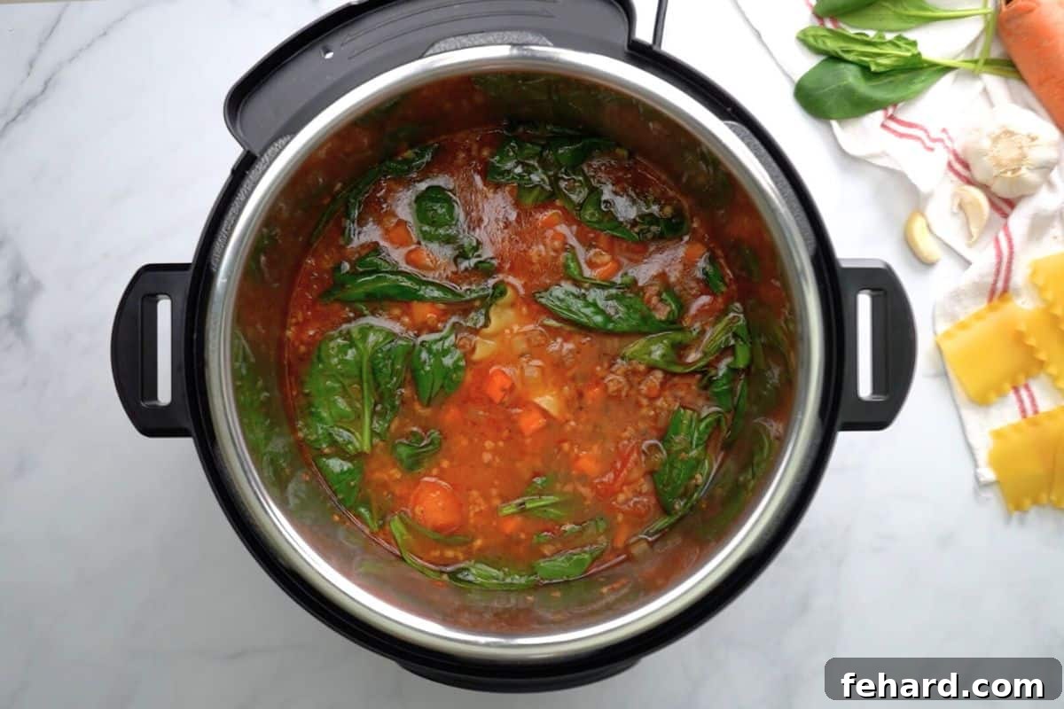 The Instant Pot open, revealing the freshly cooked lasagna soup with perfectly tender noodles, sausage, and a rich tomato base, ready for the final step of adding spinach.