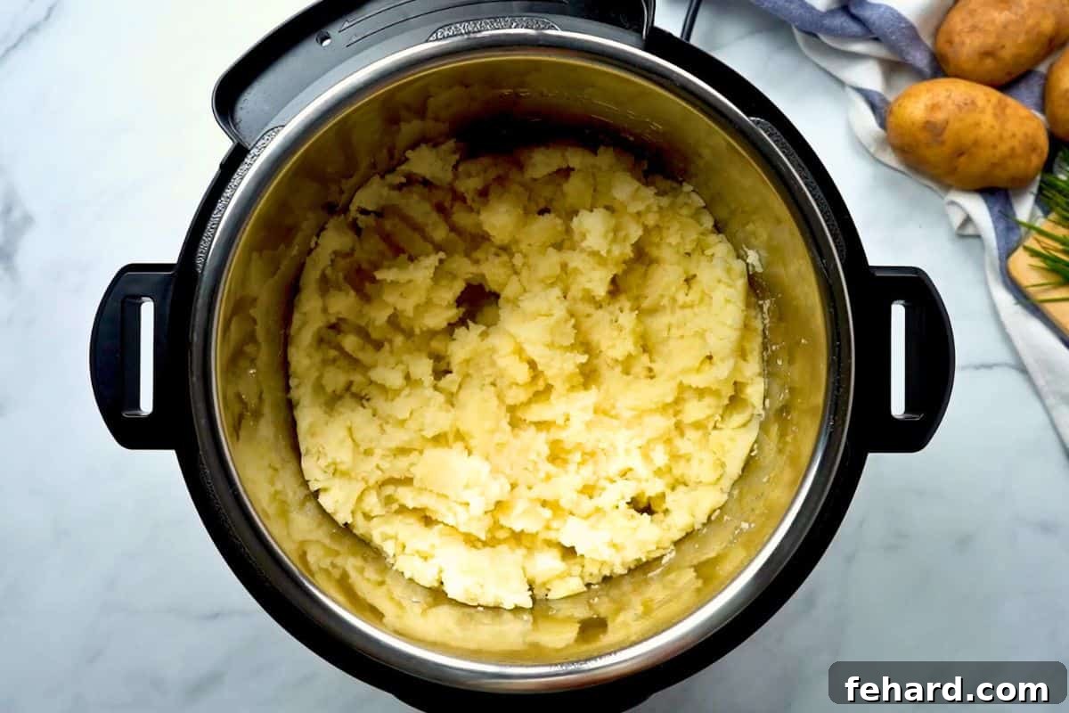 Mashed cooked potato cubes inside inner pot, turning into a smooth consistency.