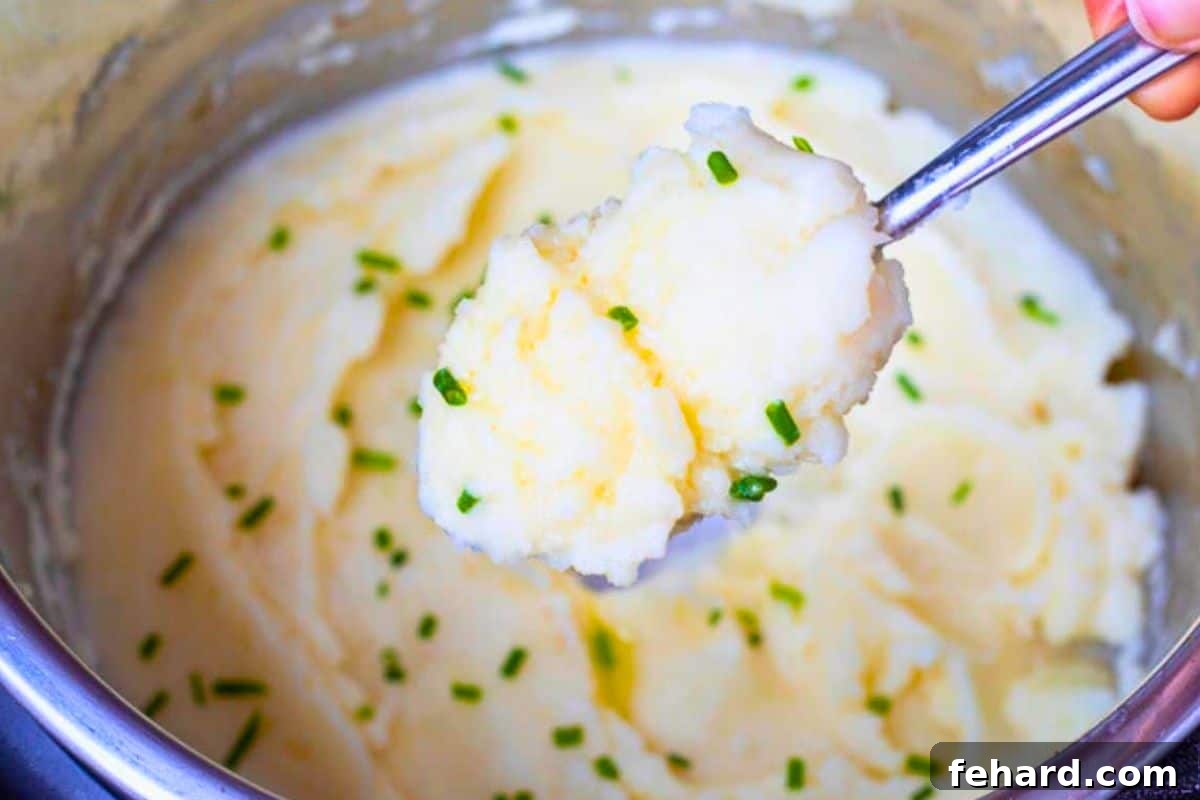 Spoon shown scooping creamy buttery mashed potatoes out of the Instant Pot, ready to be served.