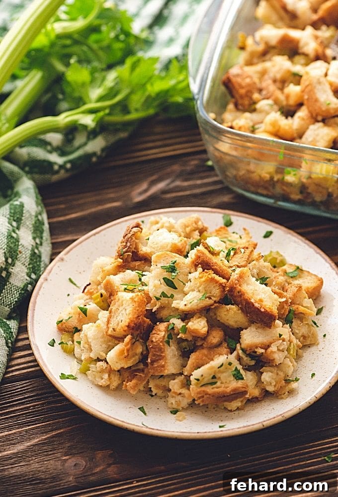 Best Bread Stuffing Recipe Classic Stuffing served on plate next to celery, highlighting its golden-brown crust and fluffy interior.