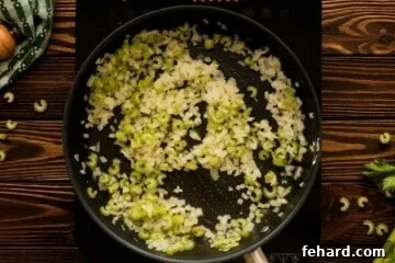 Onions and celery sautéing in butter in a pan.