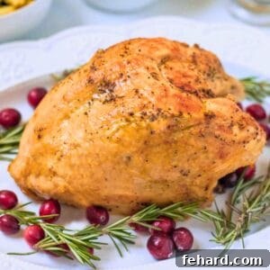 Instant pot turkey breast on white platter with crispy skin surrounded by rosemary sprigs and cranberries.