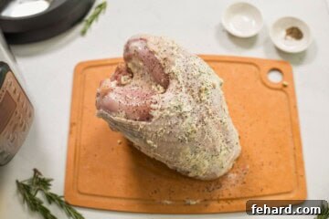 Bone-in turkey breast on wooden cutting board next to Instant Pot after being rubbed with an herb butter.