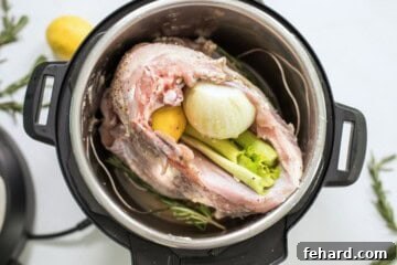 Turkey breast rubbed with herb butter breast side down with celery and lemon inside cavity of turkey inside instant pot on trivet.