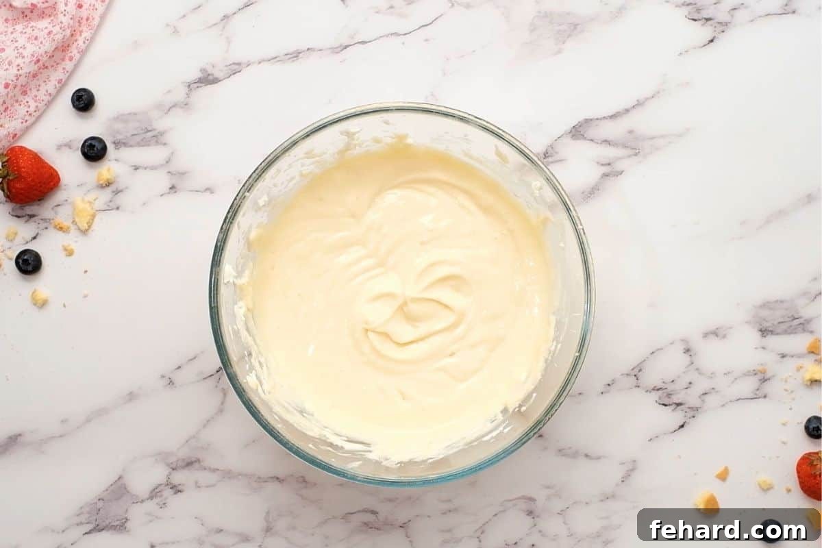 A mixing bowl filled with smooth, creamy cheesecake batter, perfectly prepared and ready to be portioned into mini muffin cups.