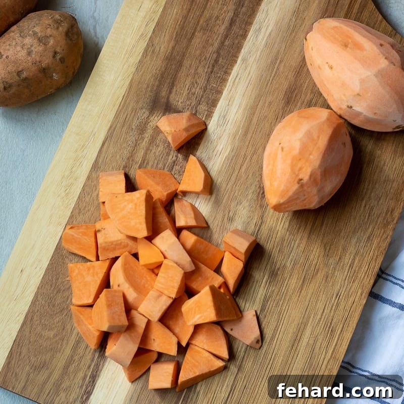Healthy Mashed Sweet Potatoes Chopped sweet potatoes arranged neatly on a wooden cutting board, ready for cooking.