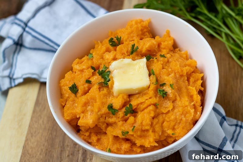 Easy Recipe for Mashed Sweet Potatoes Healthy mashed sweet potatoes in a white bowl, topped with a melting pat of butter, ready to be served.