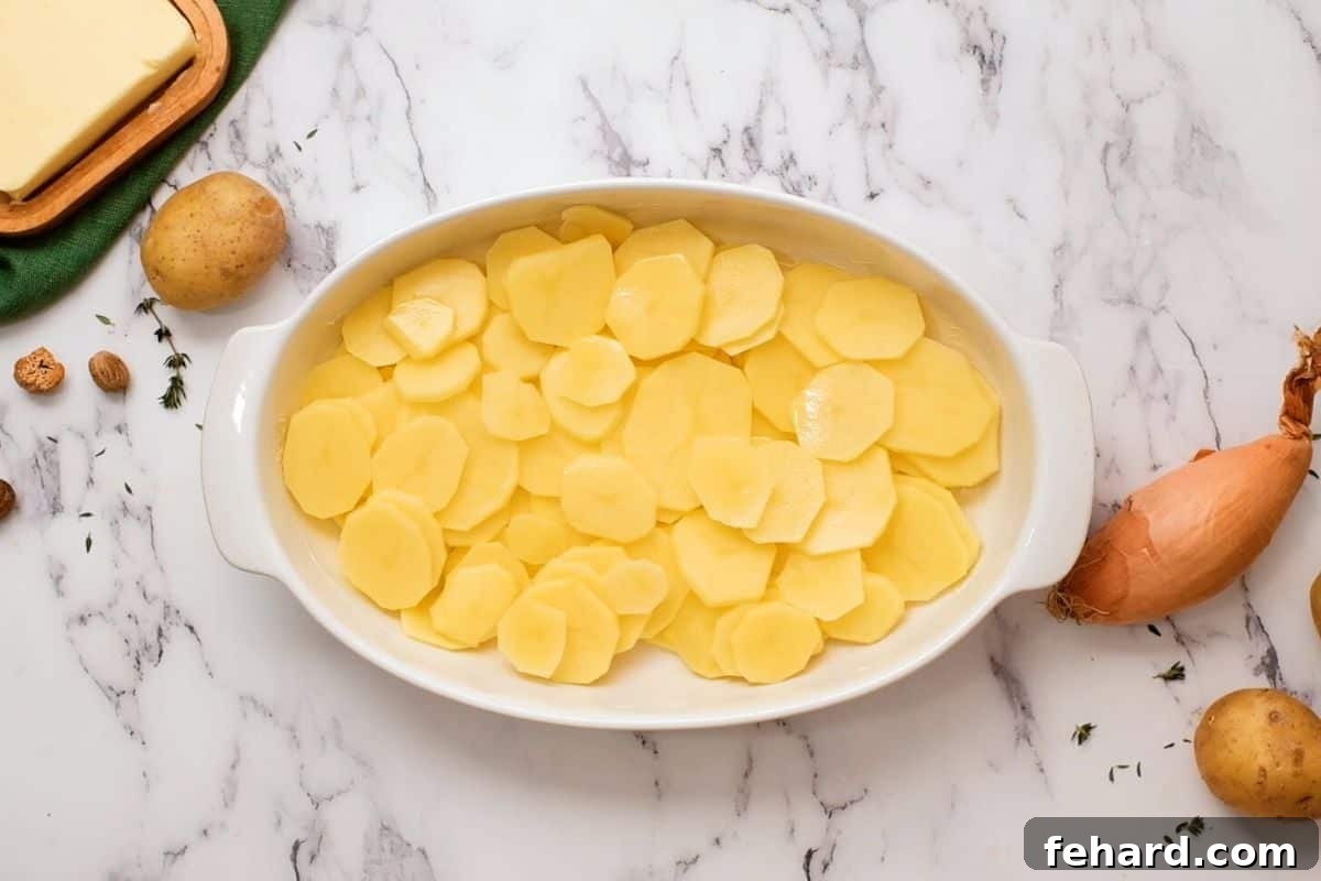 Homemade Scalloped Potatoes Sliced yukon gold potatoes in white casserole dish.
