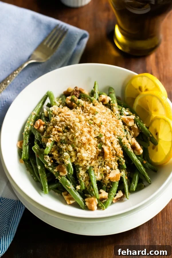Overhead image of a vibrant bowl of roasted green beans generously topped with golden garlic panko crumbs, ready to be served.