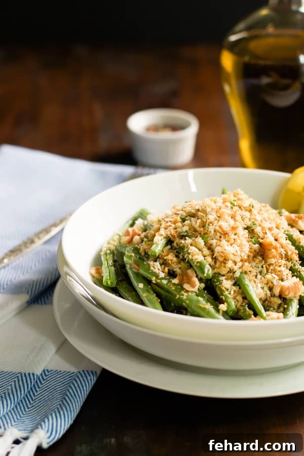 A close-up side view of a serving bowl filled with roasted green beans, perfectly coated with golden-brown garlic panko for an inviting crunch.