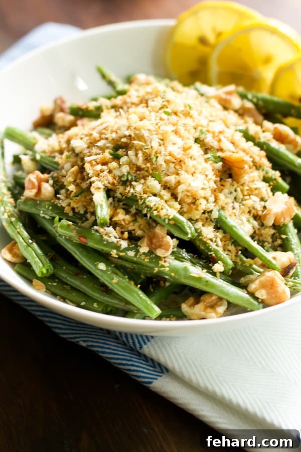 A vibrant, extreme close-up shot of a bowl of roasted green beans with garlic panko, showcasing the texture of the crumbs and the fresh green color.