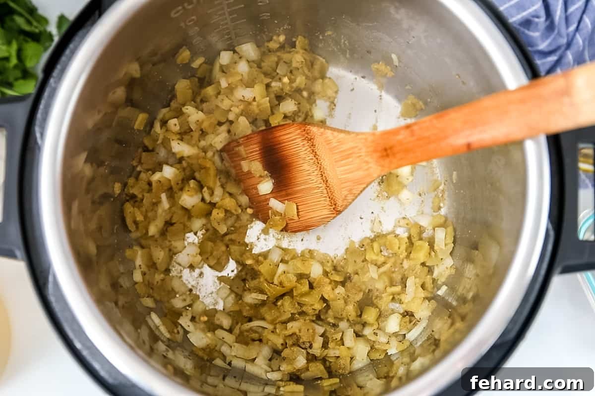 Sautéing Aromatics for White Chicken Chili Instant Pot Green chiles and onions sauteed in inner pot of instant pot.