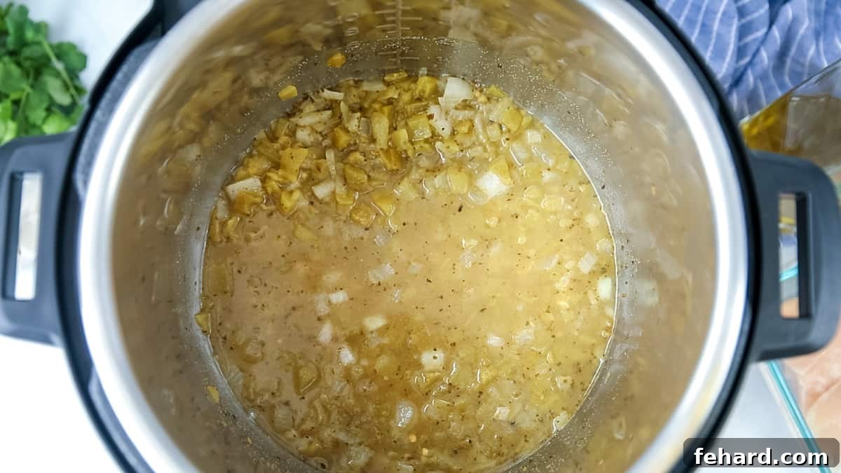 Deglazing the Instant Pot for White Chicken Chili Recipe A bit of liquid in inner pot with green chiles and onions.
