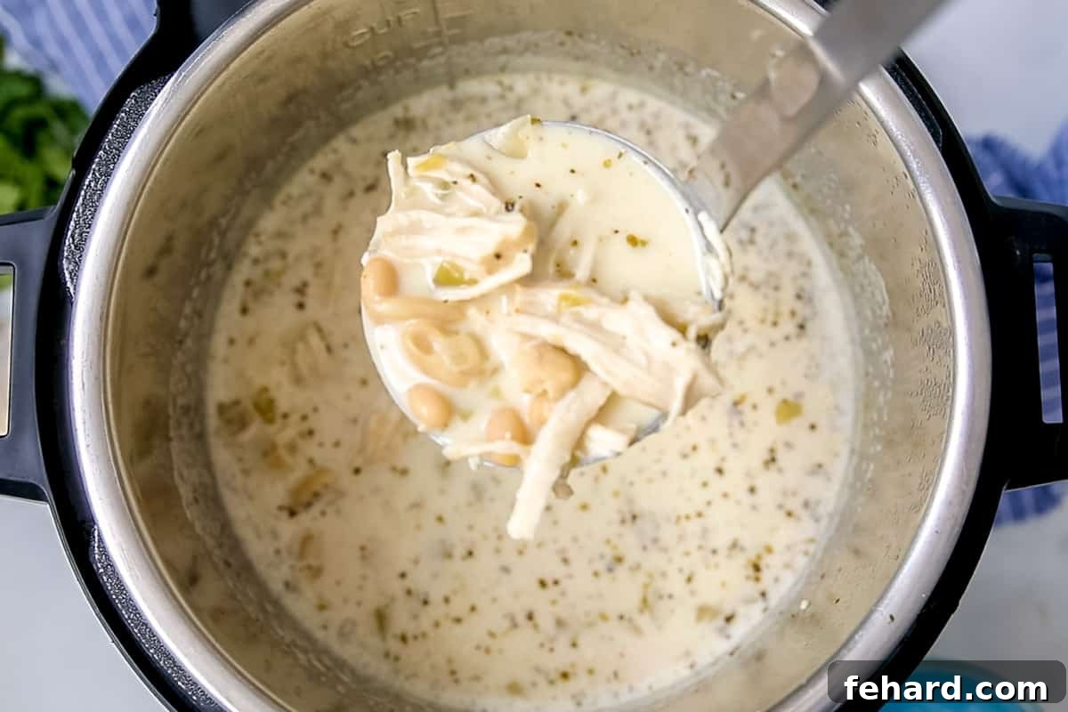 Pressure Cooker White Chicken Chili Ready to Serve Ladle of white chicken chili coming out of the instant pot.