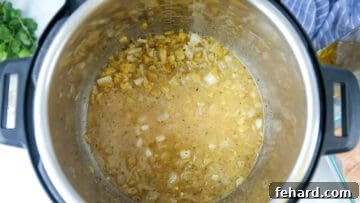 Ultimate Instant Pot White Chicken Chili 4 A bit of liquid in inner pot with green chiles and onions.